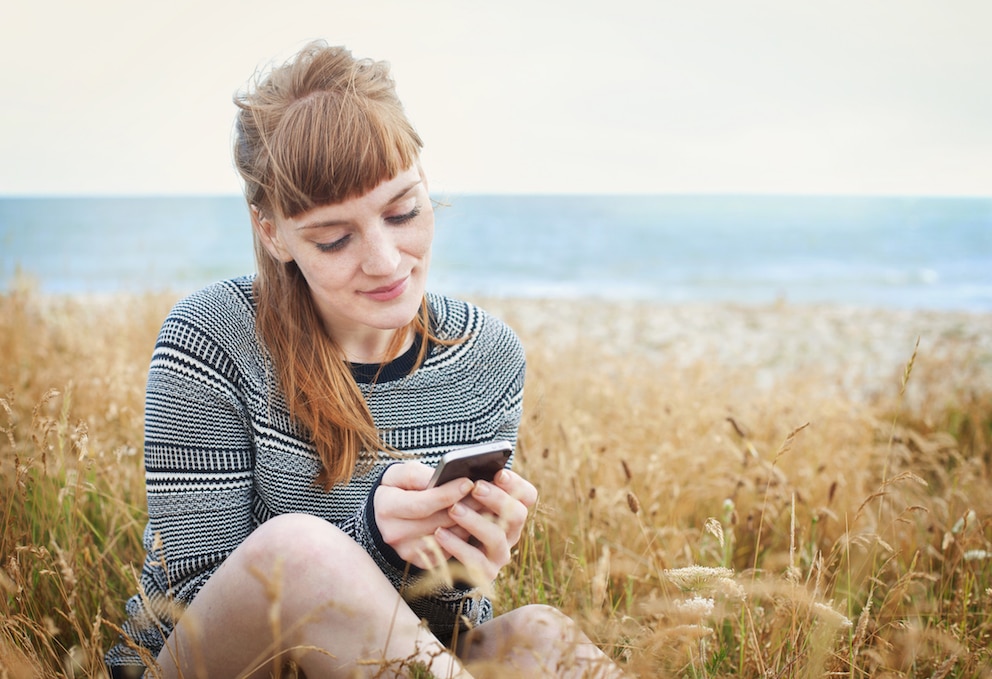 Frau mit Handy am Strand