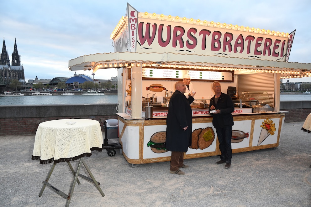 Die „Tatort“-Kommissare Freddy Schenk (Dietmar Bär) und Max Ballauf (Klaus J. Behrendt) snacken an der Wurstbraterei