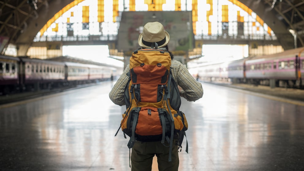 Backpacker mit Rucksack am Bahnhof