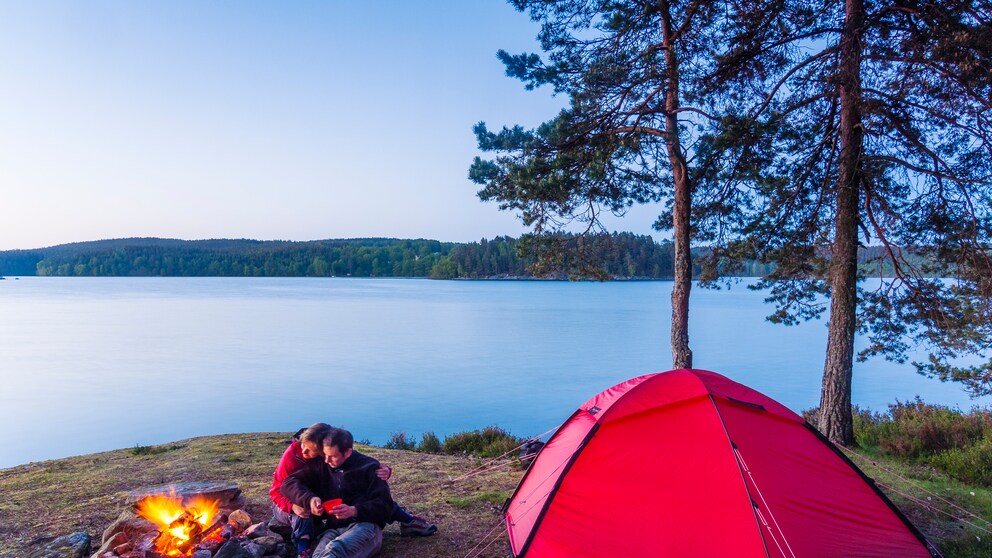 Paar am Lagerfeuer beim Campen am See