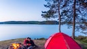 Paar am Lagerfeuer beim Campen am See