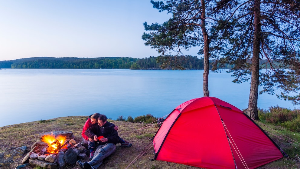 Paar am Lagerfeuer beim Campen am See