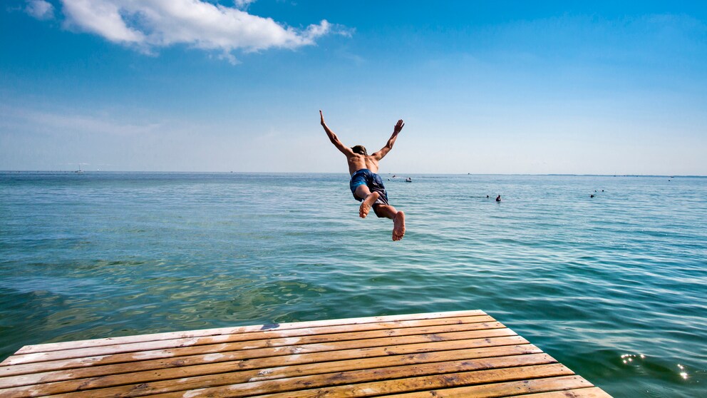 Ein Badeurlauber springt auf der Ostseeinsel Fehmarn ins Meer