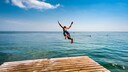 Ein Badeurlauber springt auf der Ostseeinsel Fehmarn ins Meer