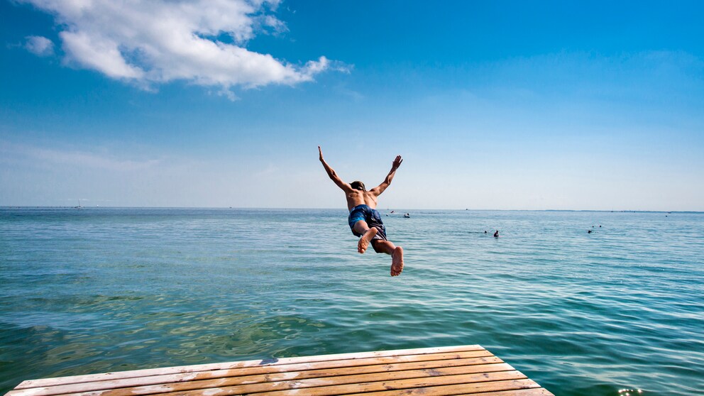 Ein Badeurlauber springt auf der Ostseeinsel Fehmarn ins Meer