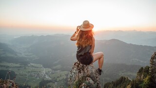 Alleinreisende Frau blickt auf Berge