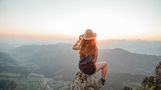 Alleinreisende Frau blickt auf Berge