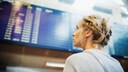 Frau guckt am Flughafen auf eine Anzeigetafel