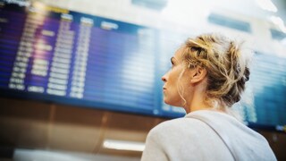 Frau guckt am Flughafen auf eine Anzeigetafel