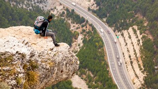 Ein Mann sitzt auf einem Felsen und Blick tief herab
