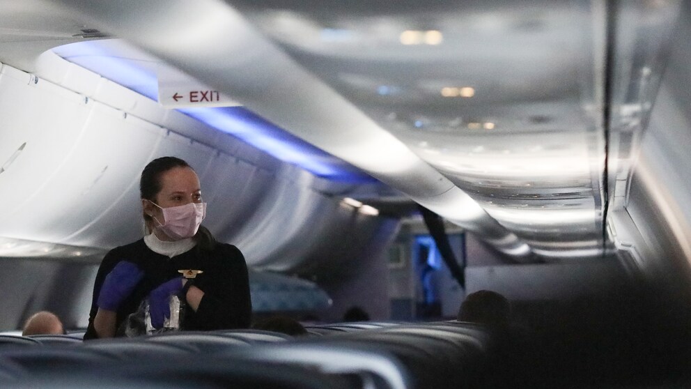 Flugbegleiterin mit Mundschutz im Flugzeug