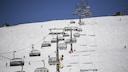 Ein schneebedeckter Hang, über den ein Skilift fährt