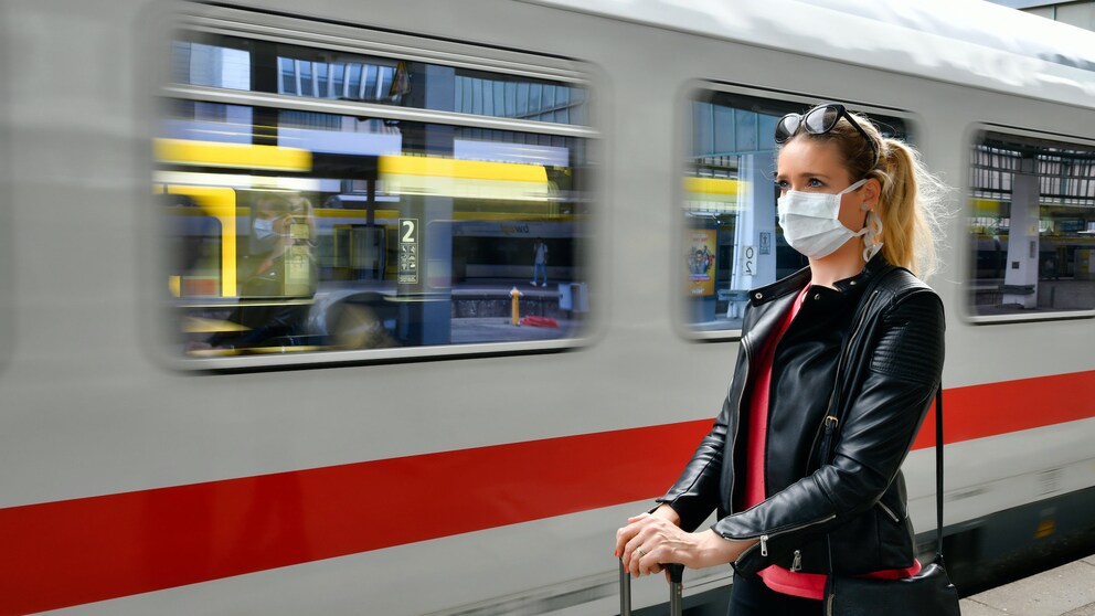 Frau mit Mundschutz am Bahnhof