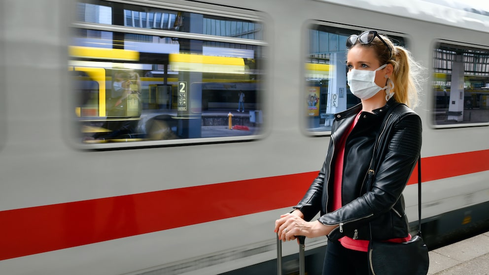 Frau mit Mundschutz am Bahnhof