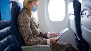 Frau im Flugzeug mit Maske