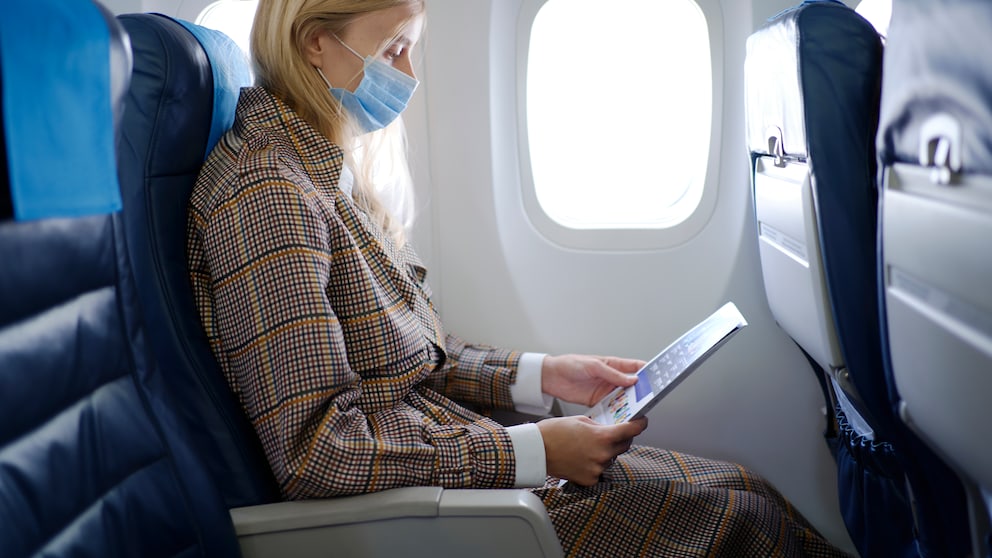 Frau im Flugzeug mit Maske