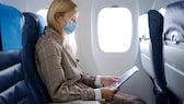 Frau im Flugzeug mit Maske