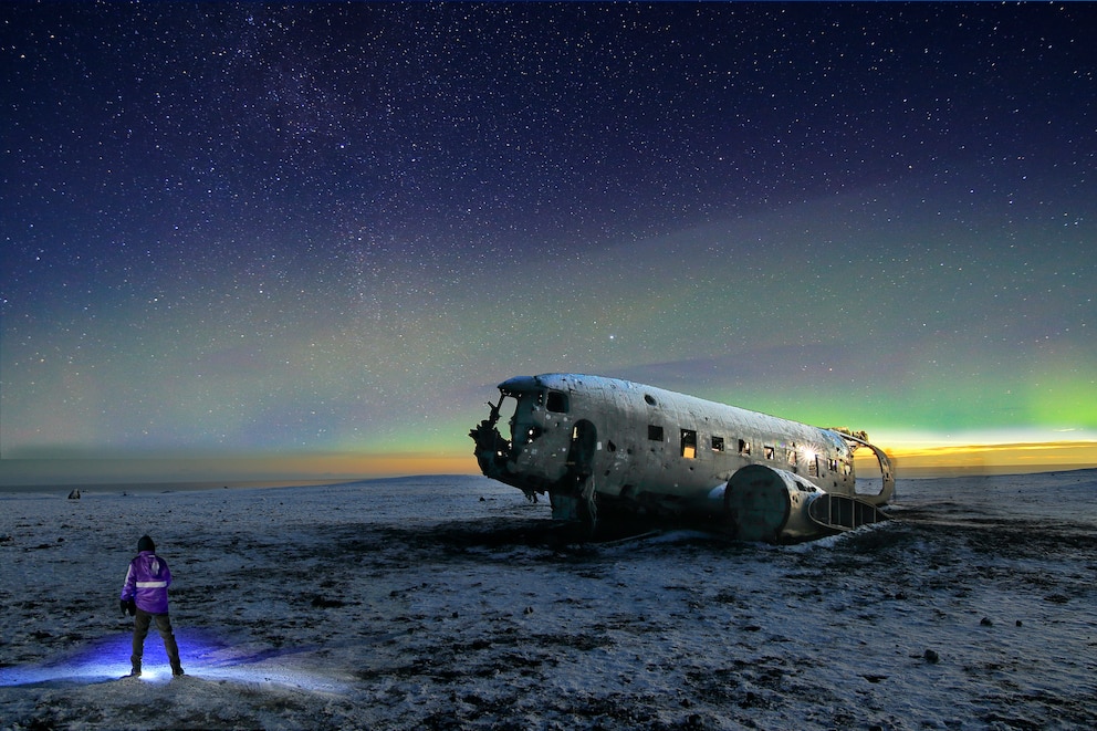 In Island sind etwa zwischen Mitte August und Mitte März Polarlichter zu sehen. Das Flugzeugwrack wirkt dann fast mystisch.