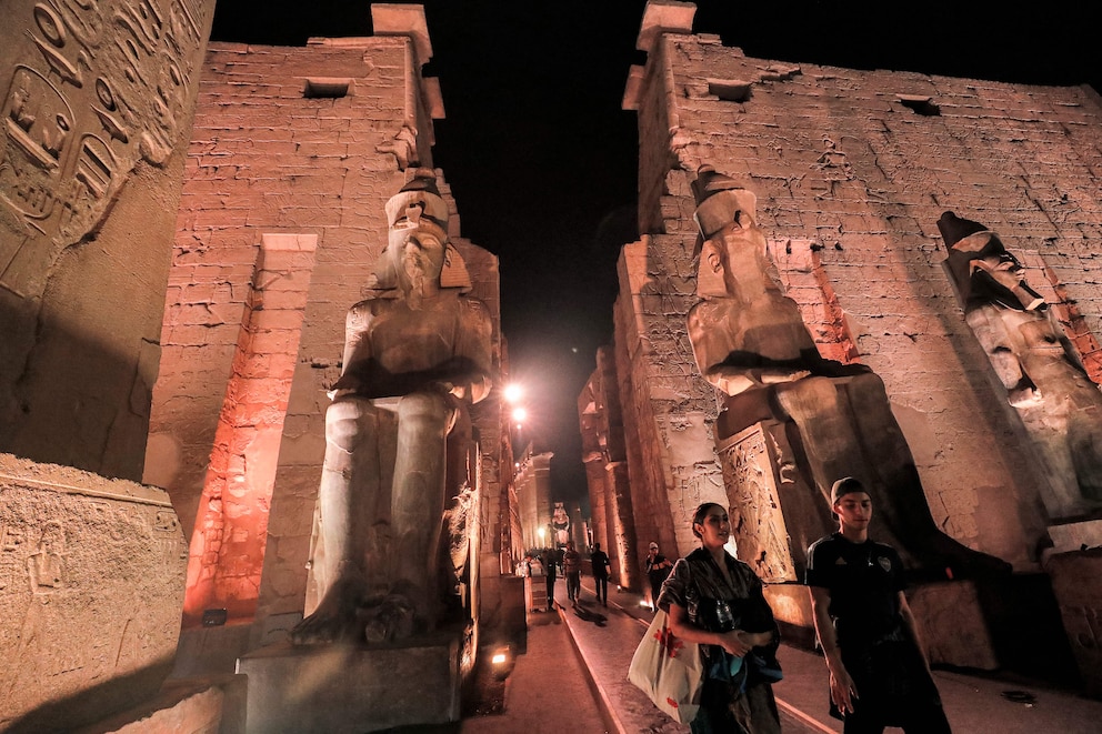 Besucher spazieren an den Statuen des altägyptischen Pharaos Ramses II (1303-1213 v. Chr.) aus dem Neuen Reich im Luxor-Tempel (erbaut um 1400 v. Chr.) in der gleichnamigen Stadt im Süden Ägyptens vorbei