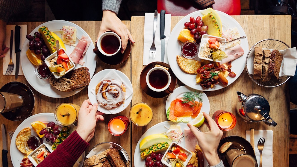 Voll gedeckter Frühstückstisch mit Brötchen, Kaffee und Brot