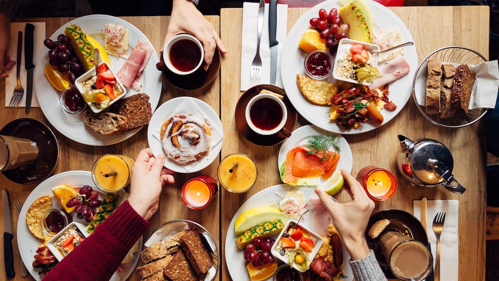 Voll gedeckter Frühstückstisch mit Brötchen, Kaffee und Brot