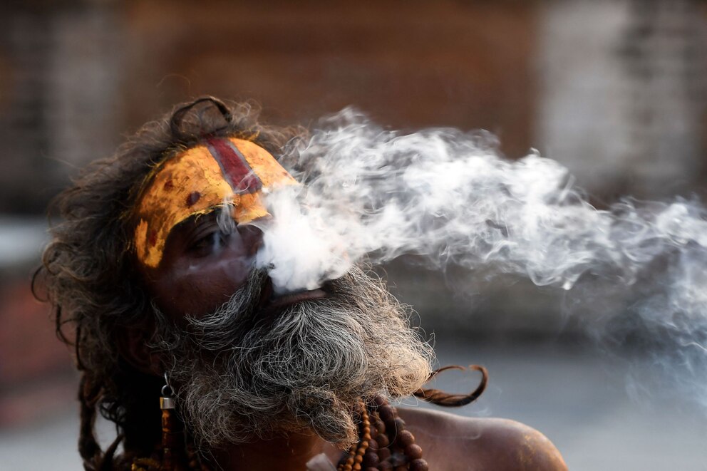 Ein Sadhu, ein heiliger hinduistischer Mönch, raucht vor dem Pashupatinath-Tempel in Kathmandu Marihuana r
