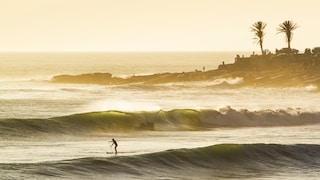 Surfer bei Sonnenuntergang am Atlantischen Ozean in Marokko