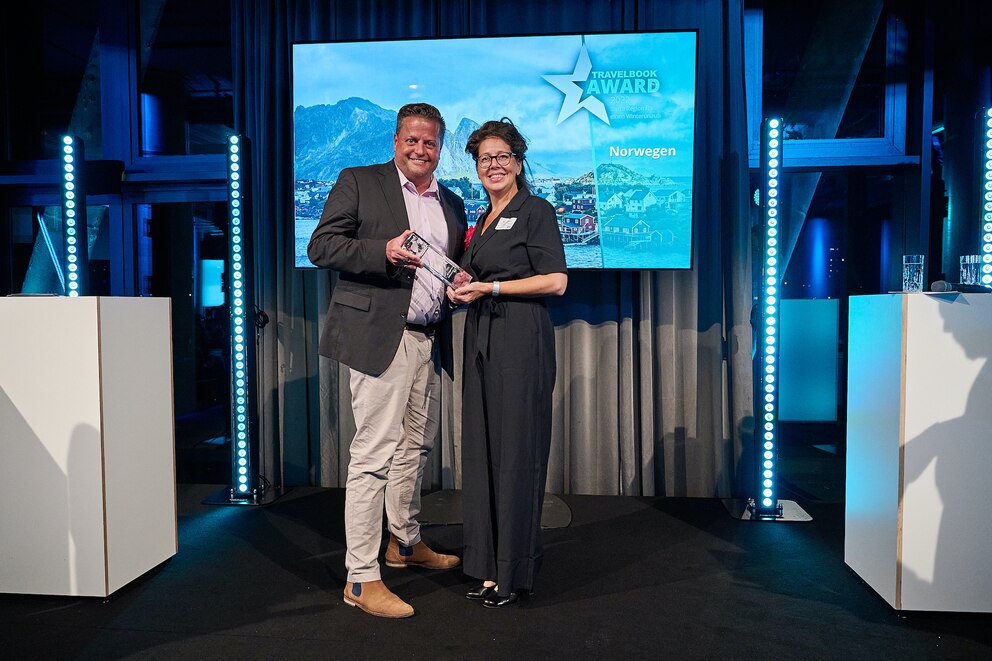 Aage Dünhaupt, Jurymitglied und Laudator, übergibt den TRAVELBOOK AWARD für das beste Winterreiseziel Ulrike Peters von Visit Norway