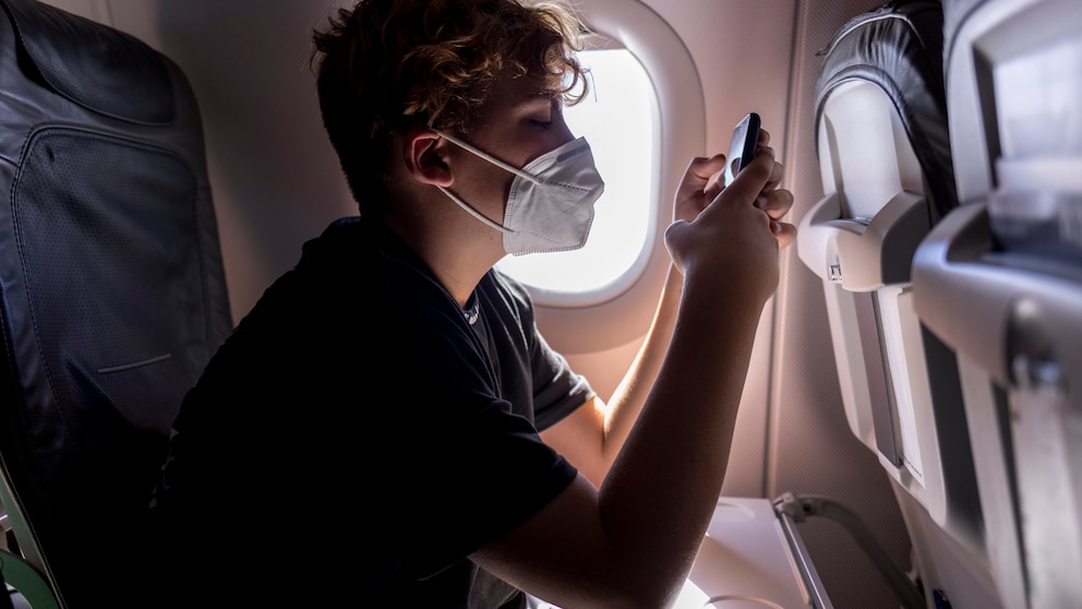 Junge benutzt Smartphone im Flugzeug