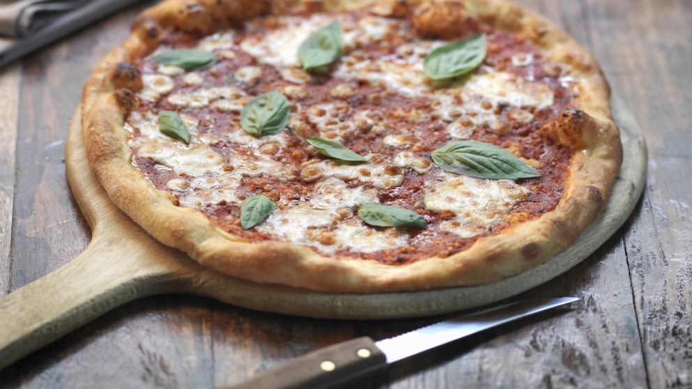 Pizza Margherita auf einem Holzbrett / Pizza-Preise in Europa