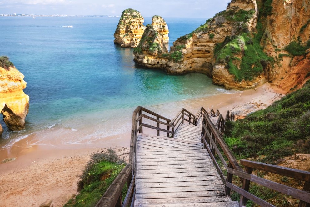 A wooden staircase leads directly down to Praia do Camilo beach