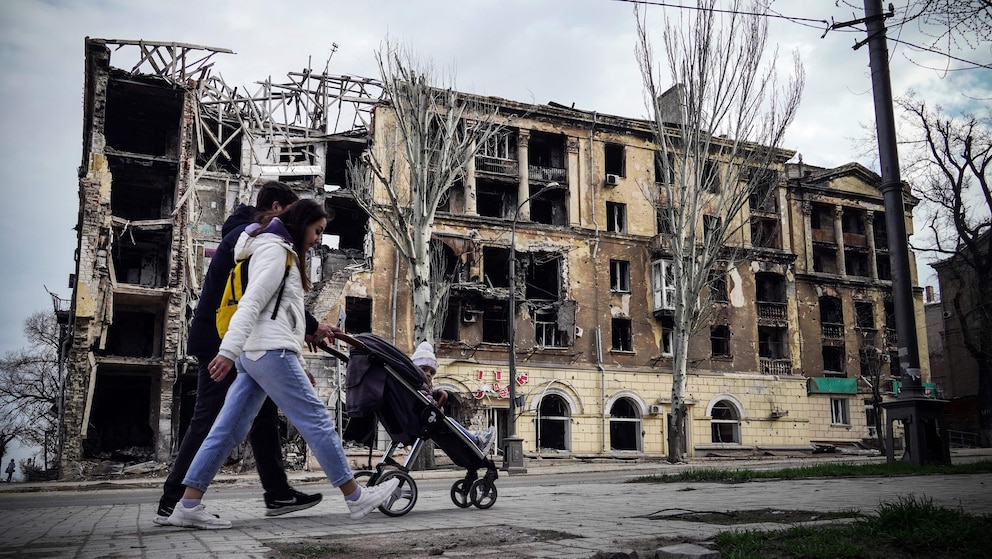 Eine kleine Familie vor einem zerstörten Haus im Südosten der Ukraine 