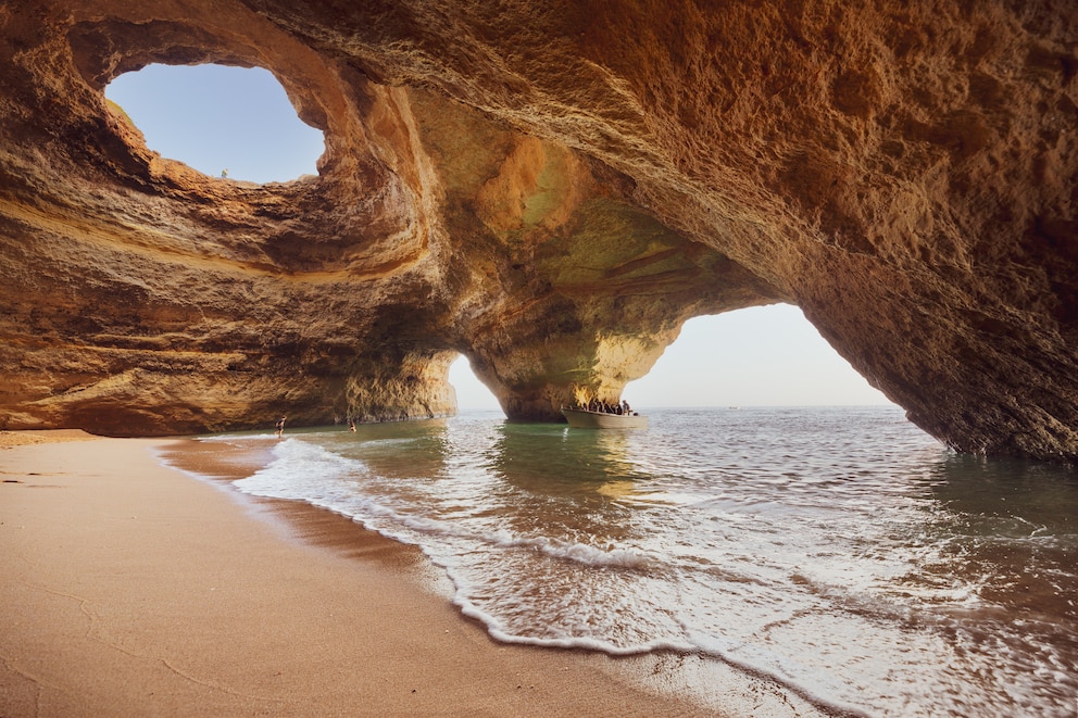 Im Süden Portugals an der Algarve liegt die Höhle von <a href="https://www.travelbook.de/news/algarve-benagil-hoehle">Benagil</a>. Sie ist vor allem im Sommer ein Touristenmagnet – und das zu Recht. Durch die Öffnung in der Decke scheint tagsüber ganz viel Sonnenschein in die Höhle hinein, wodurch die Felsformationen honigfarben leuchten. Die Höhle kann man schwimmend, mit einem Kajak oder einem Stand-up-Paddle erreichen.&nbsp;