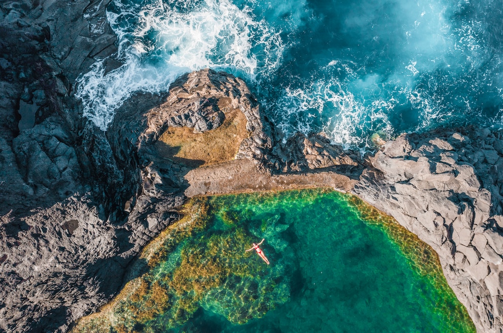 Auf der portugiesischen Insel Madeira liegt eine Frau nahe Seixal in einem Naturpool ganz in der Nähe der tosenden Wellen des Meeres