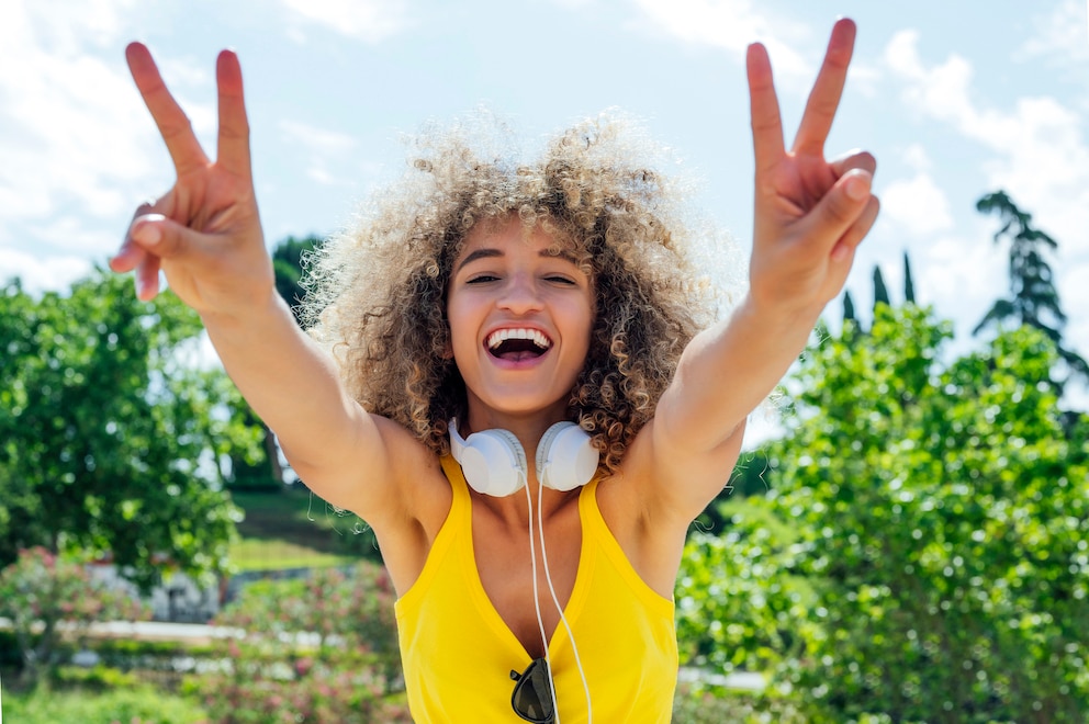 Eine Lächelnde Frau hält ein Peace Sign in die Kamera