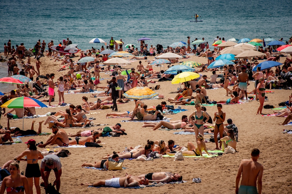 Menschen kühlen sich am Strand La Barceloneta in Barcelona ab. Eine aktuelle Studie zeigt, dass mehr als die Hälfte der Kreuzfahrtpassagiere, die Barcelona besuchen, der Meinung sind, dass es zu viele Touristen in den angesagten Vierteln der Stadt gibt.