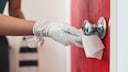 Frau beim Desinfizieren der Türklinke im Hotelzimmer