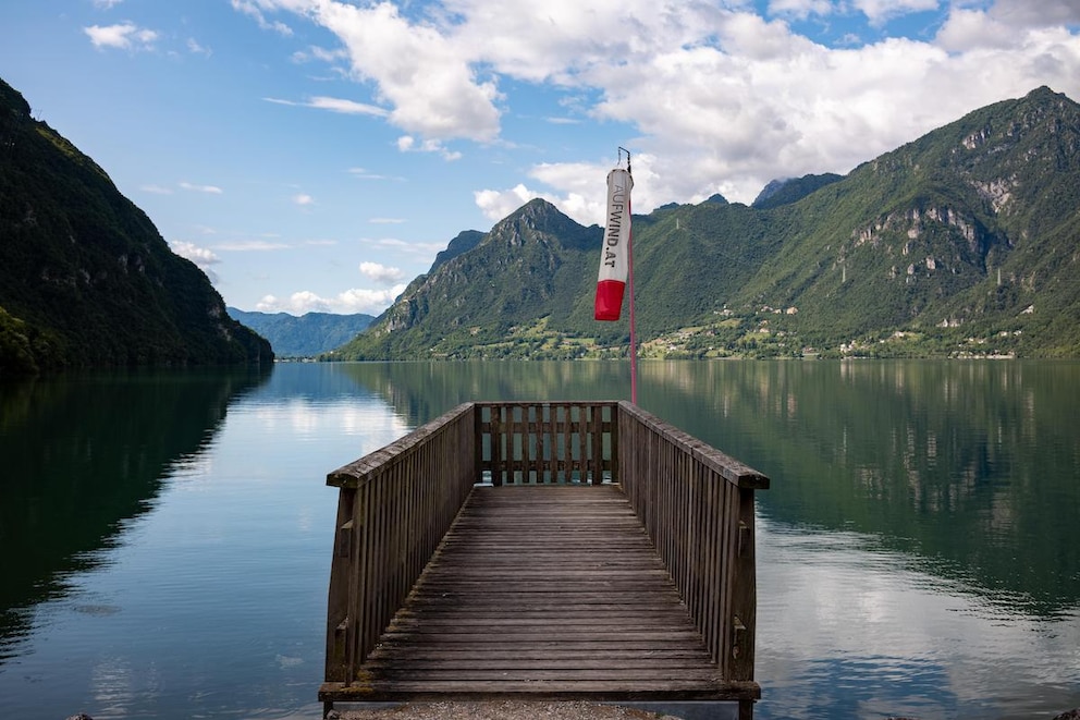 Holzbrücke am Idrosee mit grünen Bergen im Hintergrund