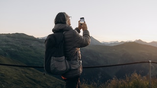 Handynutzung in der Schweiz: Tourist fotografiert Bergpanorama