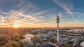 München im Sommer: Sommer in München: Einen der wohl schönsten Sonnenuntergänge der Stadt gibt es im Olympiapark zu bestaunen