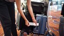 Frau bringt Strichcode-Aufkleber an Koffer an