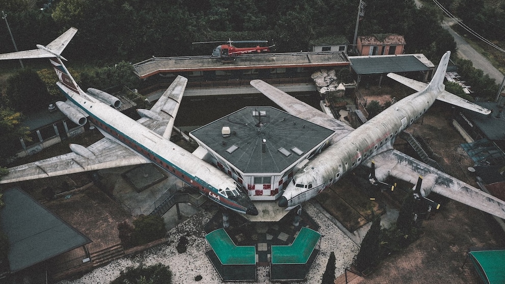Das verlassene Flugzeug-Restaurant in Italien aus der Luft aufgenommen: Zwei Flugzeuge stehen an einem Kontroll-Tower, im Hintergrund ist ein Hubschrauber zu sehen. Foto: Ludwig P. Bäßler / Instagram <a href="https://www.instagram.com/loopingludi/" target="_blank" rel="noreferrer noopener">loopingludi</a>
