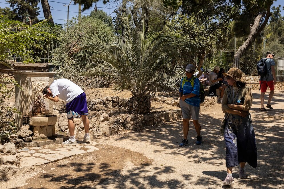 Ein Mann erfrischt sich während seines Besuchs am Tempel des Olympischen Zeus in Athen an einem Trinkbrunnen