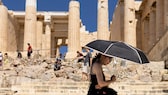 Eine Touristin sucht Schatten unter einem Schirm während ihres Besuchs auf der Akropolis. Griechenland ist in diesem Jahr besonders früh von großer Hitze in Europa betroffen.