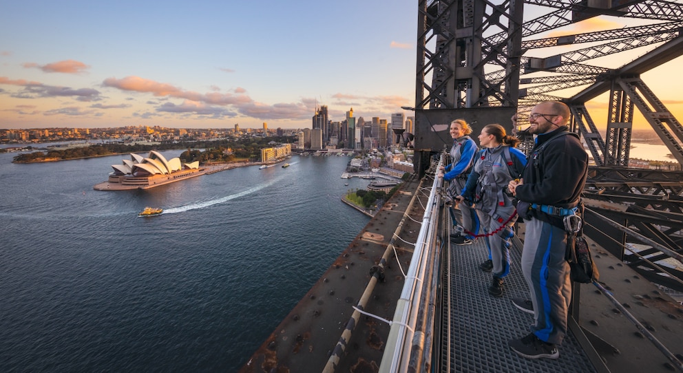Freunde, die in der Abenddämmerung die BridgeClimb Sydney Erfahrung erleben und über den Hafen in Sydney schauen