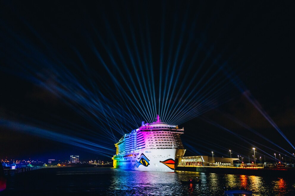 Zu sehen ist das riesige Schiff AIDA bei Nacht, welches eine Lichtershow vorführt.