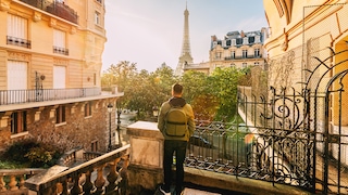 Reisender mit Rucksack vor dem Eiffelturm: Unsere Autorin nennt fünf Dinge, die sie vor ihrem Frankreich-Urlaub gerne gewusst hätte