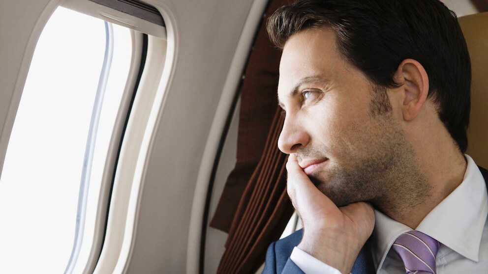 Mann schaut aus einem Flugzeugfenster