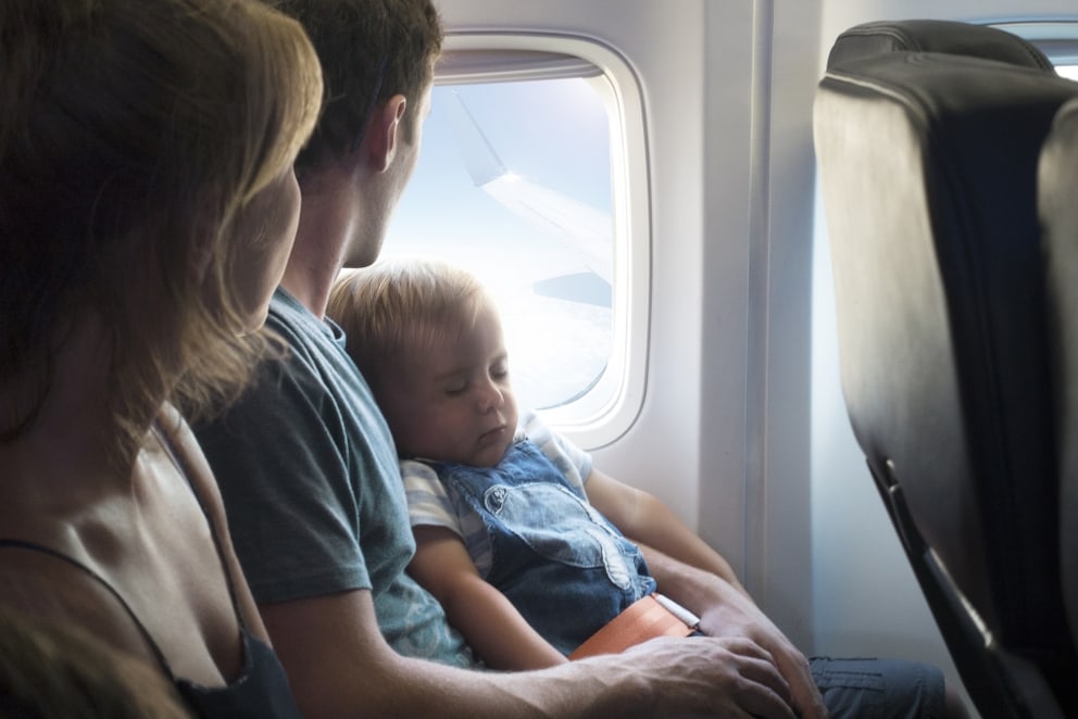 Eltern mit Baby auf dem Schoß während eines Fluges