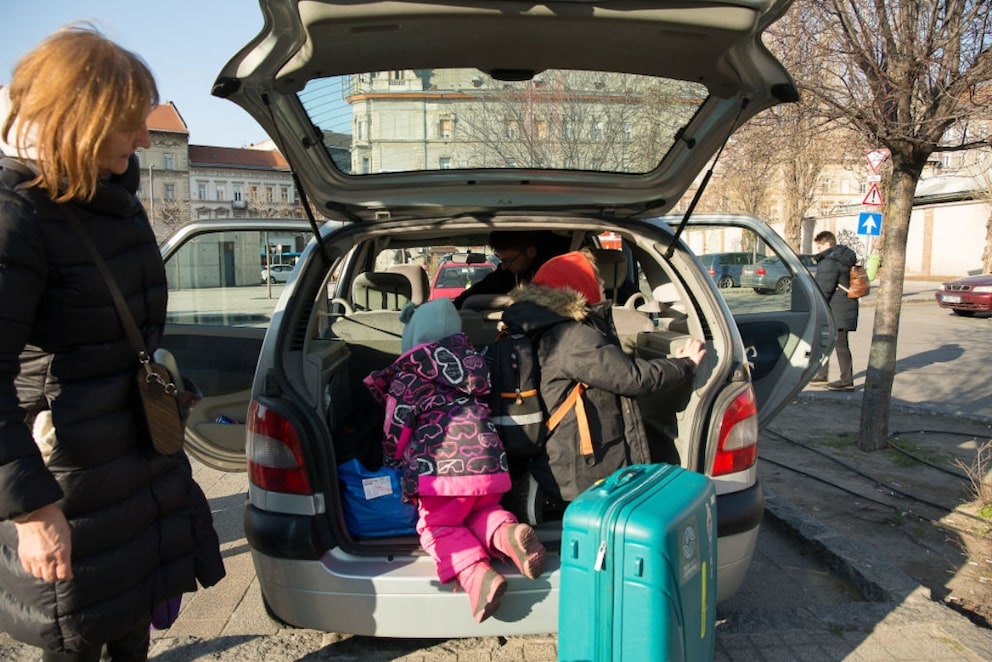 Mutter und Kinder packen Koffer in das Auto